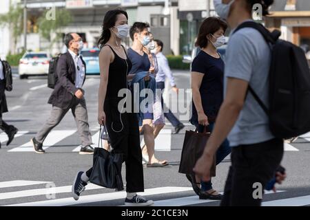 Tokyo, Japon. 15 juin 2020. Les piétons portant des masques faciaux marchent sous la chaleur dans la zone commerçante de Ginza. Les températures ont augmenté de plus de 30 degrés Celsius dans de nombreuses régions du Japon lundi. Les gens continuent à utiliser le masque facial en raison de la pandémie du coronavirus. Credit: Rodrigo Reyes Marin/ZUMA Wire/Alay Live News Banque D'Images