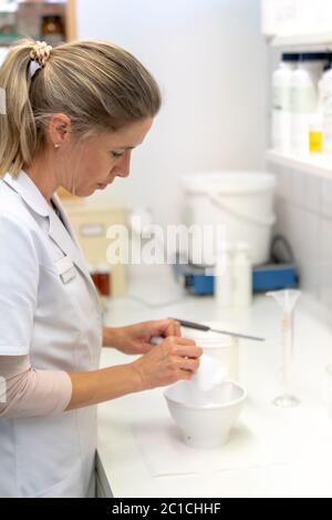 Une femme blonde pharmacien perparing un onguent médical dans le laboratoire de la pharmacie Banque D'Images