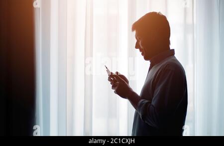 Homme regardant la silhouette de téléphone portable Banque D'Images