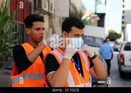 Tripoli, Libye. 10 juin 2020. Un membre de la campagne des jeunes contre Corona aide son collègue à porter un masque facial à Tripoli, en Libye, le 10 juin 2020. Lancée début mars par de jeunes volontaires libyens, la campagne "les jeunes contre Corona" s'est désormais lancée dans le nettoyage des rues et la fourniture de repas aux travailleurs étrangers et aux travailleurs indépendants qui ont été économiquement touchés par la fermeture du gouvernement depuis la mi-mars. POUR ALLER AVEC le long-la-vedette: Les jeunes Libyens se portent volontaires contre COVID-19 dans un climat de guerre Raging Credit: Mohamed Arhomah/Xinhua/Alay Live News Banque D'Images