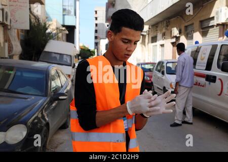 Tripoli, Libye. 10 juin 2020. Un membre de la campagne des jeunes contre Corona met des gants à Tripoli, en Libye, le 10 juin 2020. Lancée début mars par de jeunes volontaires libyens, la campagne "les jeunes contre Corona" s'est désormais lancée dans le nettoyage des rues et la fourniture de repas aux travailleurs étrangers et aux travailleurs indépendants qui ont été économiquement touchés par la fermeture du gouvernement depuis la mi-mars. POUR ALLER AVEC le long-la-vedette: Les jeunes Libyens se portent volontaires contre COVID-19 dans un climat de guerre Raging Credit: Mohamed Arhomah/Xinhua/Alay Live News Banque D'Images