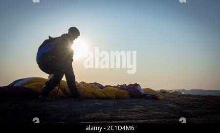 Le parapente se prépare à voler en plein air contre le ciel du coucher du soleil. Parachute dans le sac à dos en plein air Banque D'Images