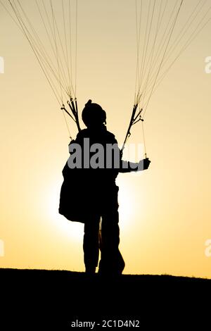 Le parapente se prépare à voler en plein air contre le ciel du coucher du soleil. Parachute dans le sac à dos en plein air Banque D'Images