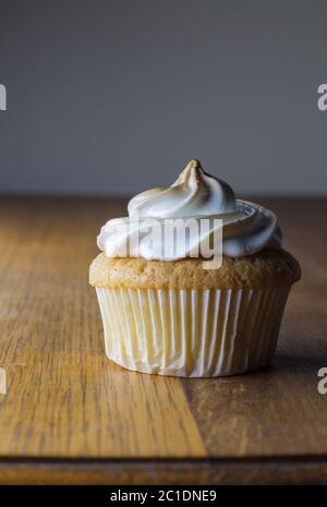 Gâteau d'une tasse avec garniture blanche sur table en bois gros plan Banque D'Images