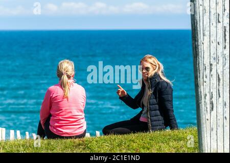 Inchydoney, West Cork, Irlande. 15 juin 2020. La plage d'Inchydoney à West Cork était aujourd'hui remplie de gens de plage, ce qui a fait le maximum du soleil et de la chaleur. Deux femmes bavardes sur les falaises au-dessus de la plage. Crédit : AG News/Alay Live News Banque D'Images