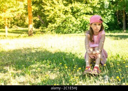 Une jeune fille rêveuse assise sur l'herbe Banque D'Images