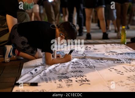 Hong Kong, Chine. 15 juin 2020. Un gamin écrit sur un chiffon pour rendre hommage à un homme qui est tombé à sa mort lors d'une manifestation il y a un an au centre commercial Pacific place de Hong Kong, en Chine, le lundi 15 juin 2020. Les autorités de Hong Kong et leurs soutiens à Pékin ont fait pression sur les politiciens de l'opposition par une série d'arrestations et de déclarations pointues. Plusieurs législateurs pro-démocratie ont été accusés ces dernières semaines de se joindre à eux ou d'inciter des personnes à participer à des manifestations rejetées par la police crédit: May James/ZUMA Wire/Alay Live News Banque D'Images