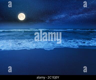 plage et mer par une nuit nuageux. vue magnifique sur les vagues qui roulent la côte sous un ciel lumineux, sous une pleine lumière de lune Banque D'Images