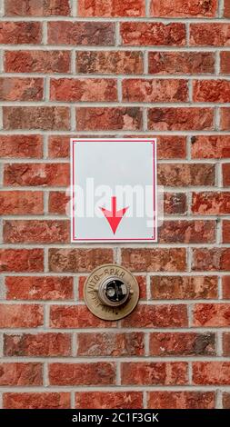 Mur en brique vertical avec flèche pointant vers l'arroseur d'incendie Banque D'Images