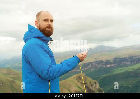 Hipster homme dans une veste bleue en utilisant un compas sur le fond dans le paysage caucasien avec un plateau Banque D'Images