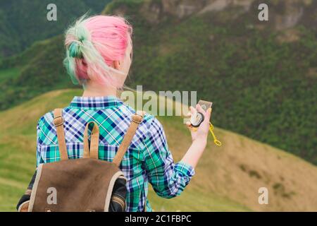 Une fille de hipster a voyagé avec un blogueur dans une chemise à carreaux et avec des cheveux multicolores en utilisant une boussole dans le fond dans le bac Banque D'Images