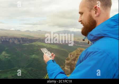 Hipster homme dans une veste bleue en utilisant un compas sur le fond dans le paysage caucasien avec un plateau Banque D'Images