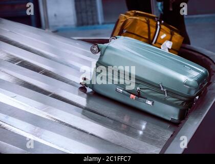 Valise sur le tapis transporteur à bagages dans la zone de retrait des bagages du terminal de l'aéroport Banque D'Images