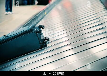 Valise sur le tapis transporteur à bagages dans la zone de retrait des bagages du terminal de l'aéroport Banque D'Images