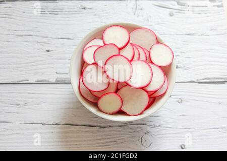 Gros plan sur les tranches de radis dans le bol. Tranches de chips de radis biologiques crus. Banque D'Images