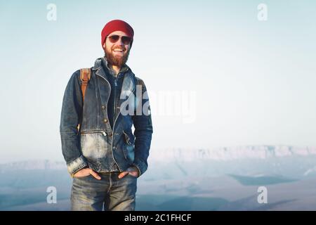 Petit homme de taille, avec barbe et moustache, portant des lunettes de soleil se posant sur le fond des montagnes Banque D'Images