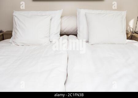 Femme de chambre lit avec oreillers blanc propre et les draps de lit dans un salon de beauté. Close-up. Flair de l'objectif à la lumière du soleil. Banque D'Images