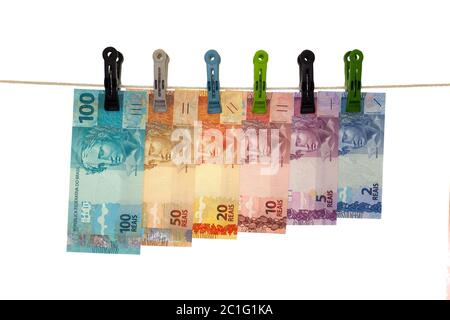 Billets de banque brésilienne dans une corde à linge - blanchiment d'argent - concept d'argent sale - isolé dans fond blanc Banque D'Images