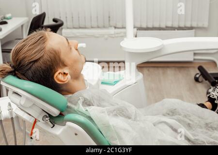 Un jeune homme satisfait dans la chaise du dentiste. Sourire à l'appareil photo. Santé et médecine. Banque D'Images