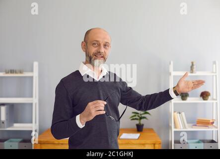 Un professeur d'âge moyen regardant la caméra utilise le chat Web, explique une stratégie d'entreprise à distance dans une pièce à la maison. Banque D'Images