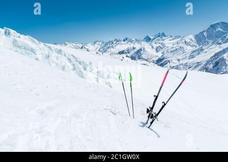 Une paire de skis et de bâtons de ski s'accumulent dans la neige sur la pente de montagne du Caucase, sur fond de m caucasien Banque D'Images