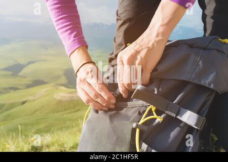 Gros plan des mains des femmes détacher la boucle du sac à dos de camp contre le fond de la vallée au soleil couchant. Visite Banque D'Images