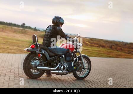 Biker homme portant une veste en cuir et des lunettes de soleil assis sur sa moto Banque D'Images