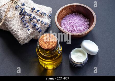 Fleur de lavande, sel de mer, pot de crème, serviettes et huile essentielle sur fond noir, vue du dessus. Aromathérapie, spa et bien-être. Mise au point sélective Banque D'Images