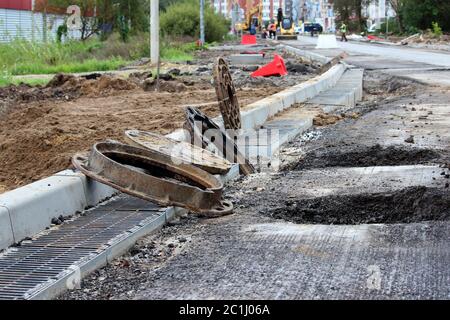 de nombreuses trappes rouillées rondes et un réseau d'eau de pluie sur le côté de la route de la ville. réparation et expansion de la route à la sortie de la Banque D'Images