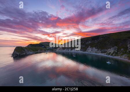 Lulworth Cove, Dorset, Royaume-Uni. 15 juin 2020. Météo Royaume-Uni. Un coucher de soleil spectaculaire à Lulworth Cove dans Dorset avec les nuages deviennent rouges à la fin d'une chaude journée ensoleillée. Crédit photo : Graham Hunt/Alay Live News Banque D'Images