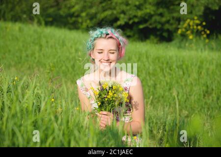 Portrait d'une jeune fille souriante heureuse dans une robe en coton avec un bouquet de fleurs sauvages Banque D'Images