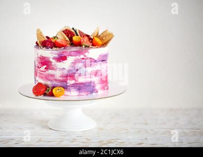 Magnifique gâteau brillant sur un support à gâteau en porcelaine décoré de fruits Banque D'Images