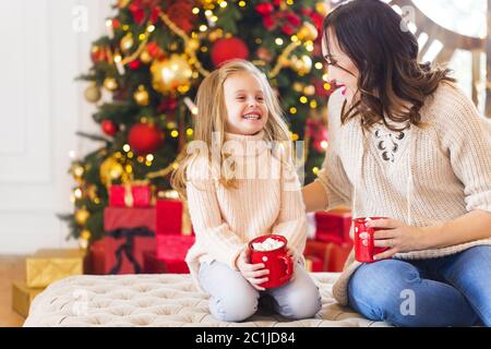 Chocolat chaud avec guimauves entre les mains de la femme heureuse et de sa fille Banque D'Images