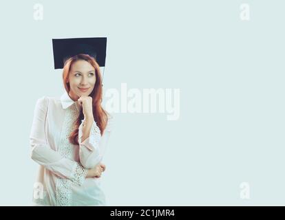 Portrait gros plan jeune belle diplômé réfléchi diplômé étudiant fille jeune femme dans le chapeau robe regardant vers le haut penser isolé lumière bleu mur de soutien Banque D'Images