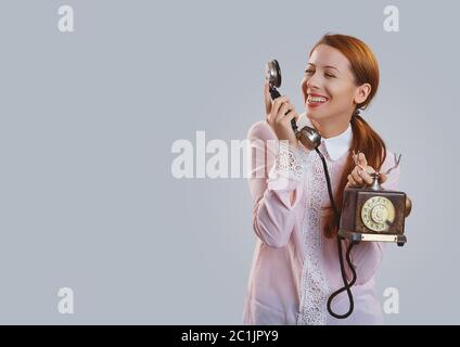 Bonne femme rouge en chemise rose parlant au téléphone et souriant à l'appareil photo Banque D'Images