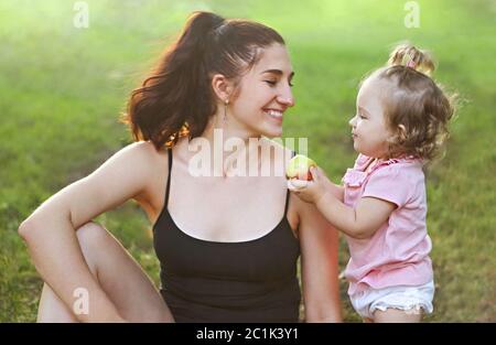 Young woman exercising with her baby girl in the park Banque D'Images