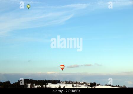 Deux ballons à air chaud survolent le paysage d'hiver de la Bavière Banque D'Images