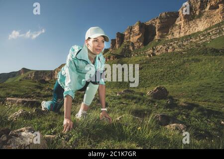 Une femme sportive était prête à courir au pied des rochers. Le coureur de fitness de la ligne de départ finie crée un été extérieur Banque D'Images