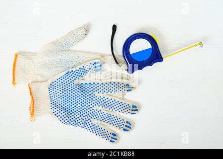 Gants de réparation avec mètre à ruban pour mesurer sur fond en bois blanc avec vue de dessus Banque D'Images