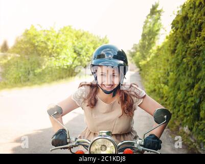 Jeune femme conduisant un scooter sur une route de campagne Banque D'Images