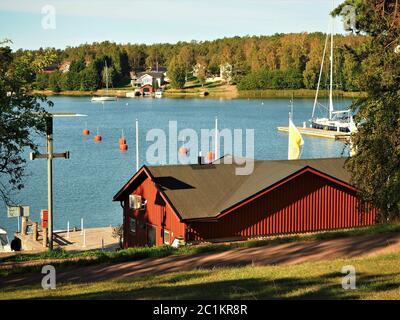 Vue sur un canal de la mer Baltique avec des bateaux à voile de Mariehamn à Aland, Finlande, à une rive boisée avec des maisons Banque D'Images