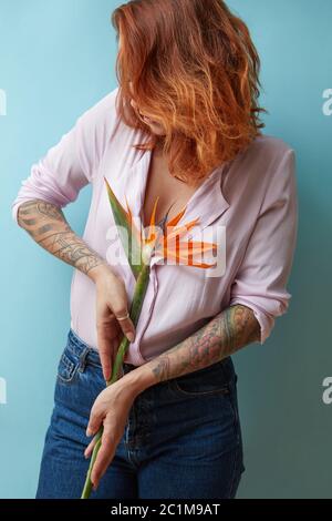 Jeune fille à cheveux rouges tenant une strelitzia sur un fond bleu Banque D'Images