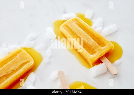 Motif de nourriture des éclaboussures et de la glace aux fruits sur un bâton avec des tranches de fond de marbre gris glacé avec espace pour le texte. Banque D'Images