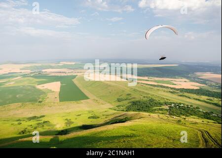 Un parapente blanc-orange survole le terrain montagneux Banque D'Images