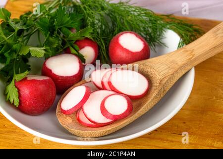 Aneth, radis et persil dans un bol. Radis hachés dans une cuillère en bois Banque D'Images