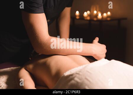 Massage spa en gros plan, sous-angle. Massage thérapeute masculin effectuant un massage du dos et des épaules à une jeune fille avec ses coudes dans une da Banque D'Images