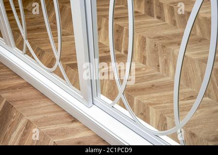 Portes-armoire à miroir coulissant avec décoration superposée. armoire blanche à miroir coulissant sur fond de parquet. Gros plan Banque D'Images