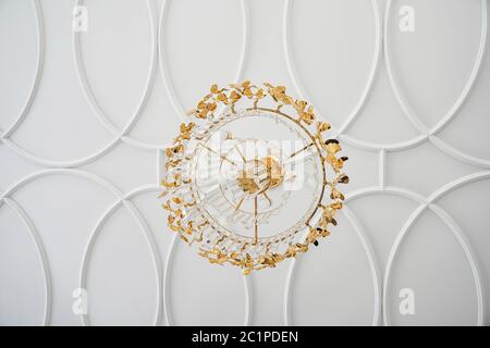 Moulures décoratives blanches avec lustre en cristal doré. Vue de dessous Banque D'Images