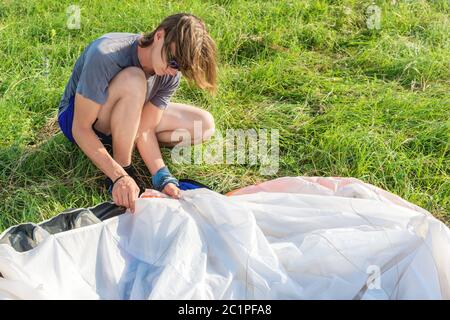 Après l'atterrissage, le parapente professionnel redresse son aile avant de l'entreposer. Concept sport de parapente Banque D'Images