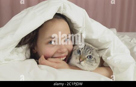 Happy teen girl baisers et des pourparlers avec Thai cat in bed Banque D'Images